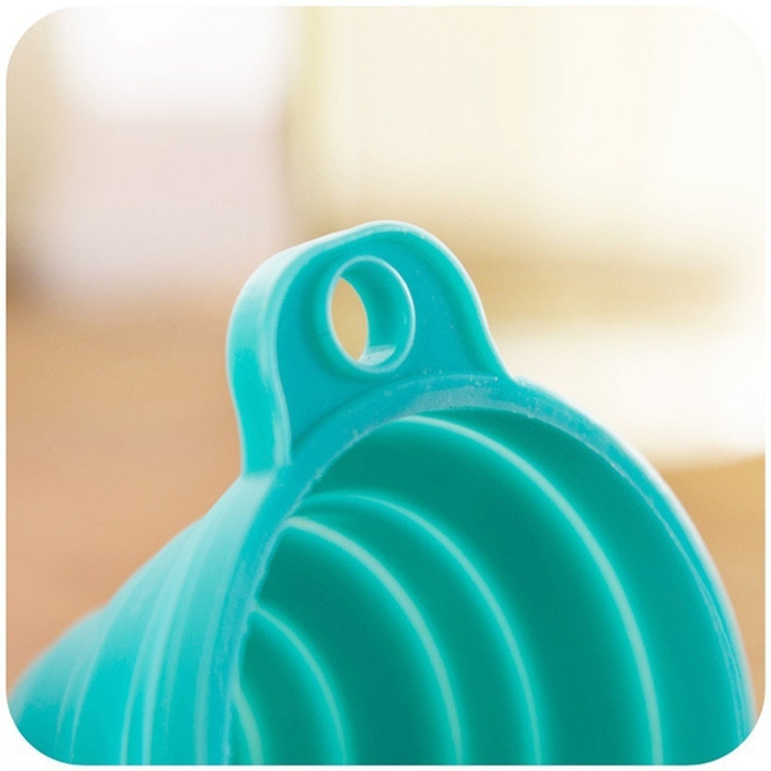 Detailed view of the narrow spout of the red silicone funnel for precise pouring.