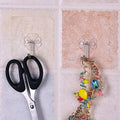 Pair of small stainless steel adhesive hooks on a white wall.