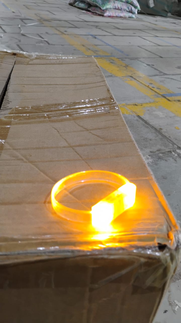An LED running bracelet brightly glowing in a dark outdoor night environment.