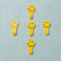 A set of five white self adhesive hooks displayed on a clean surface.