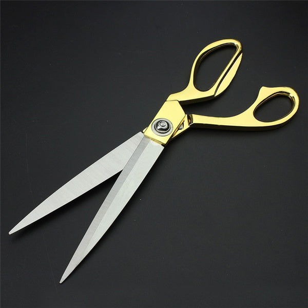 Stylish gold-plated professional cloth cutting scissors against a neutral background.
