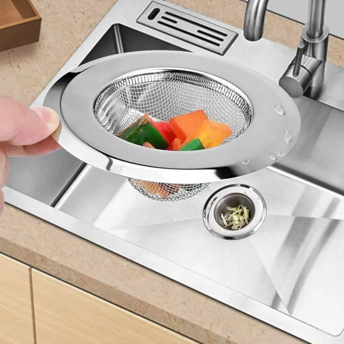 A shiny stainless steel sink strainer installed in a kitchen basin, preventing food waste.