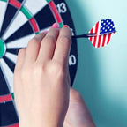 A person holding a steel tip dart, ready to throw at a dartboard.
