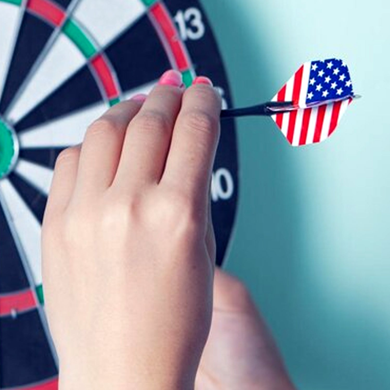 A person holding a steel tip dart, ready to throw at a dartboard.