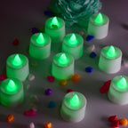 Green flameless LED tealights glowing softly on a dark surface.