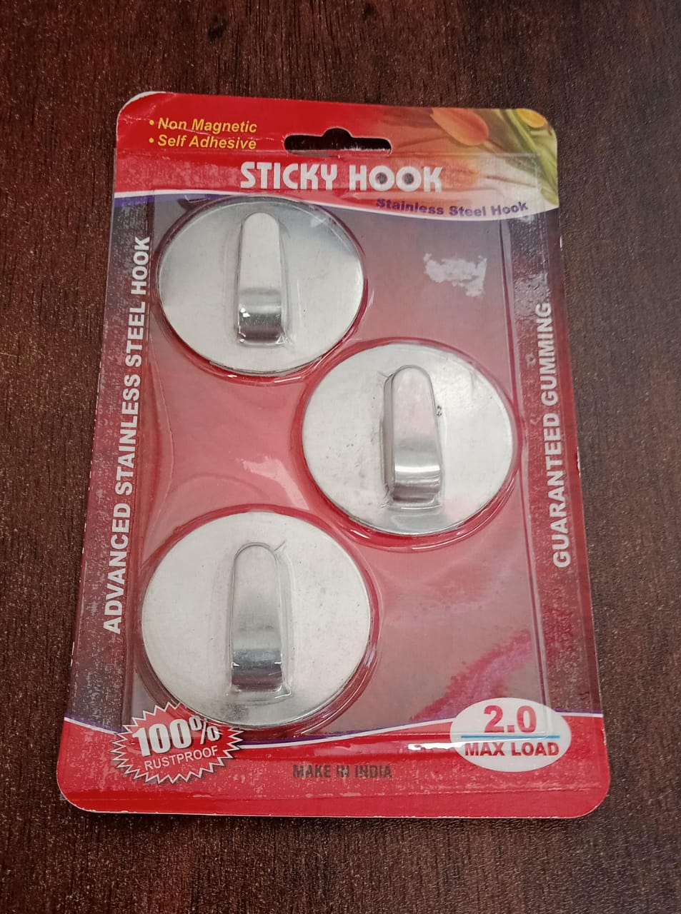 Self-adhesive hooks holding a coat and a handbag on a wall in an entryway.