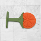 Baby's hand grasping a silicone fruit teether toy, showing ergonomic design.