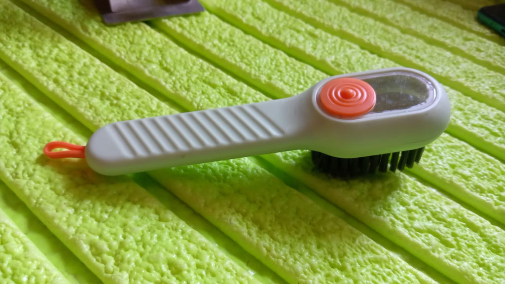 Angled view of the scrubbing brush with dispenser, highlighting its design.