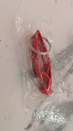 Portable metal bottle opener keychain next to keys on table