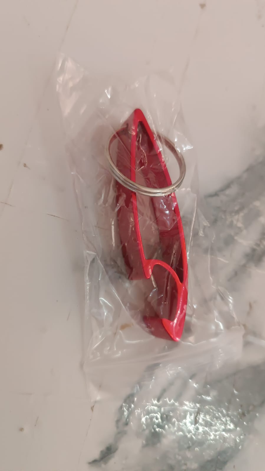 Portable metal bottle opener keychain next to keys on table
