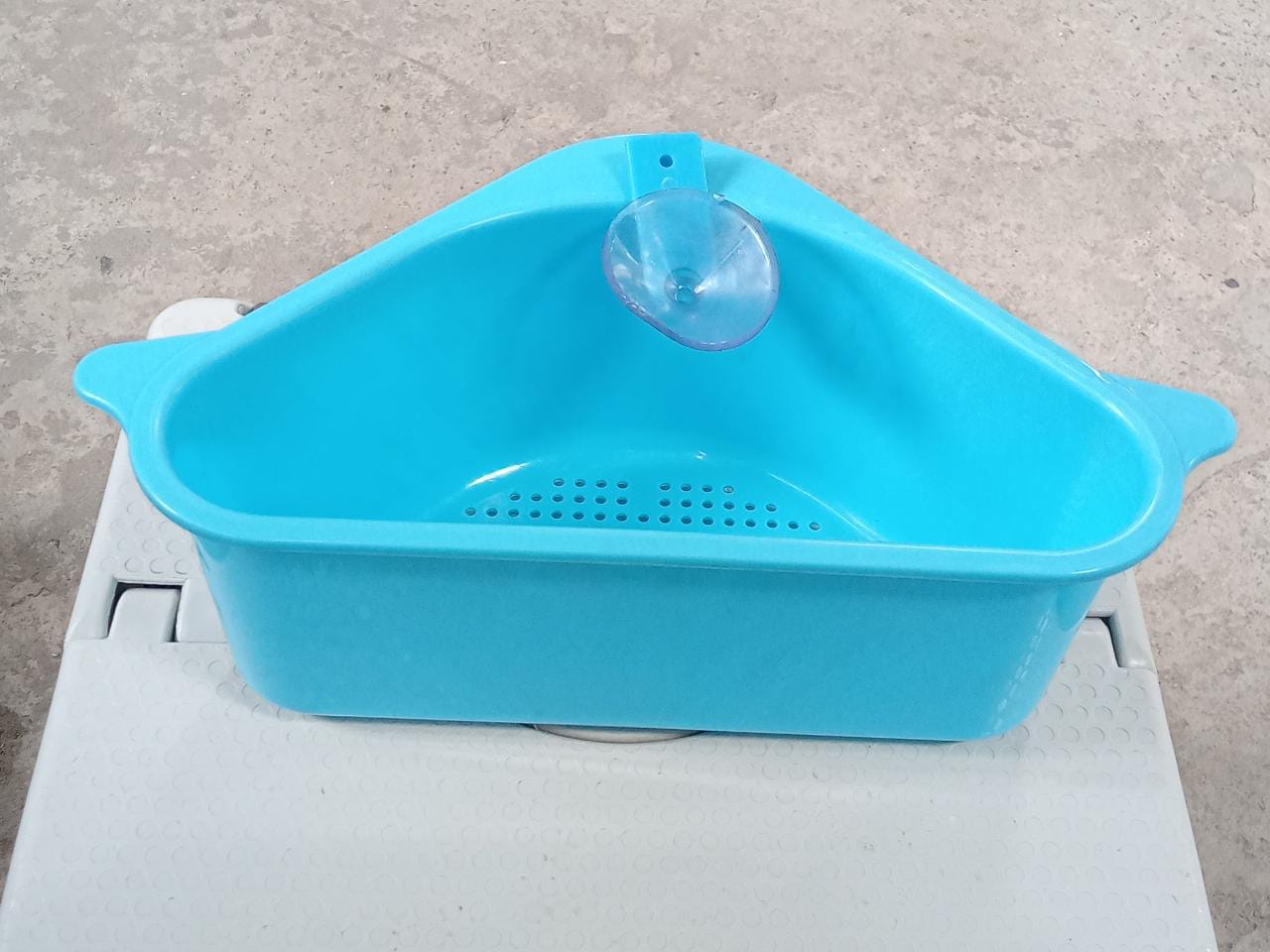 Multi-functional triangular sink drainer shelf used in a bathroom.