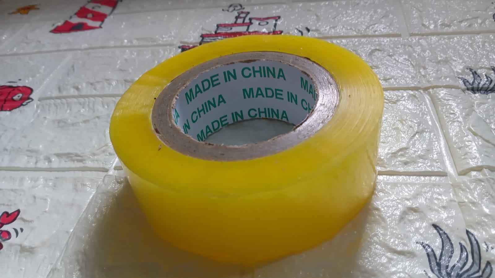 Transparent packing tape roll unwound slightly, showing its strong adhesive side.