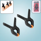 Close-up of a pair of heavy-duty spring clamps for mobile device screen repair.