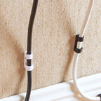 Several adhesive cable cord holders neatly attached to a wooden desk surface.