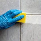 Scrub sponge demonstrating its effectiveness on a bathroom tile surface, removing grime.
