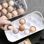 Clear plastic 12-cavity egg storage box with a lid, holding white eggs.