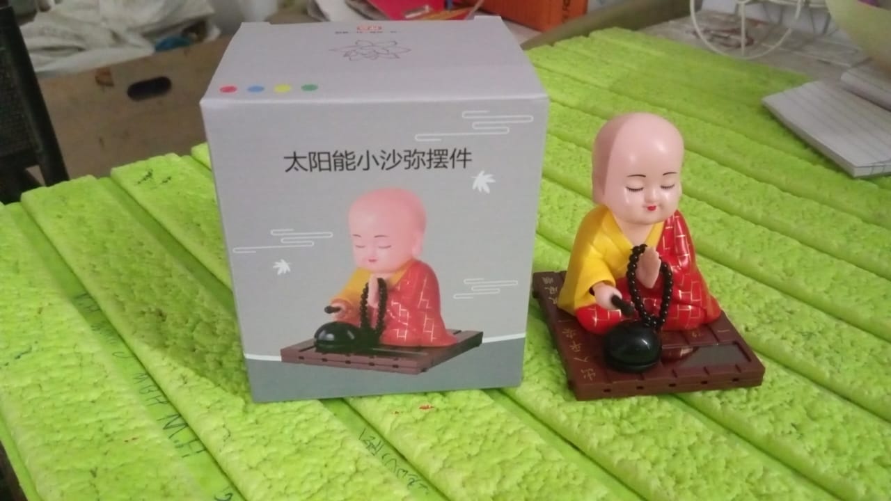 Solar Buddha Statue shown on a car dashboard, enhancing travel ambiance.