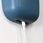A wall mounted phone holder installed beside a bed, holding a phone for convenient access and charging.