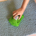 Handheld carpet roller brush efficiently cleaning dust and crumbs from a patterned rug.