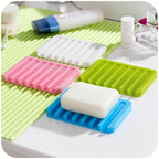 White silicone soap holder with self-draining design for shower use.
