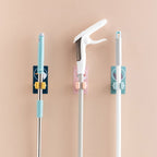 Multiple self-adhesive mop and broom holders neatly arranged on a wall.