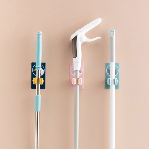 Multiple self-adhesive mop and broom holders neatly arranged on a wall.