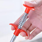 A hand using the drain cleaner to clear a bathroom floor drain.