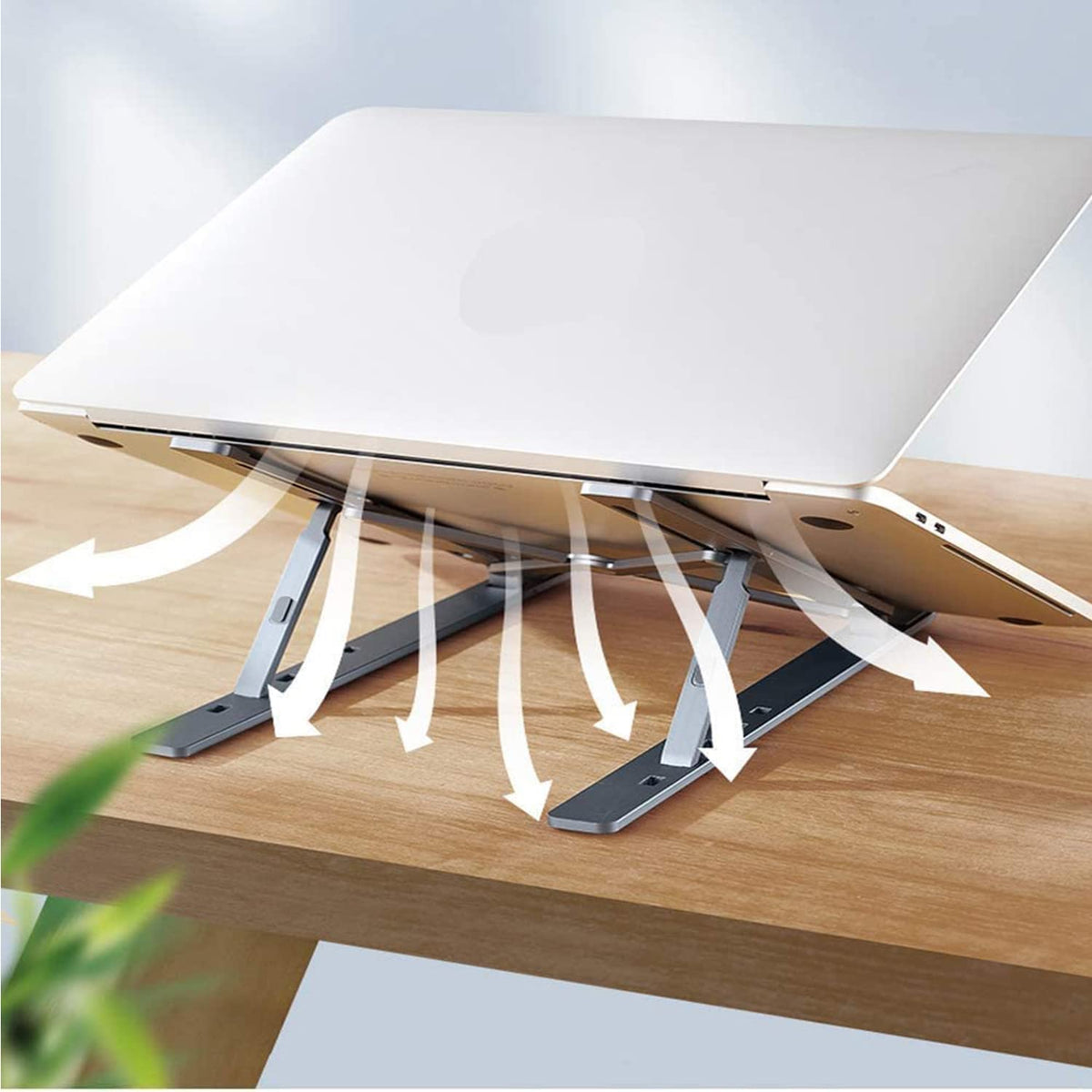 A silver metal portable laptop stand elevating a laptop for ergonomic comfort on a desk.