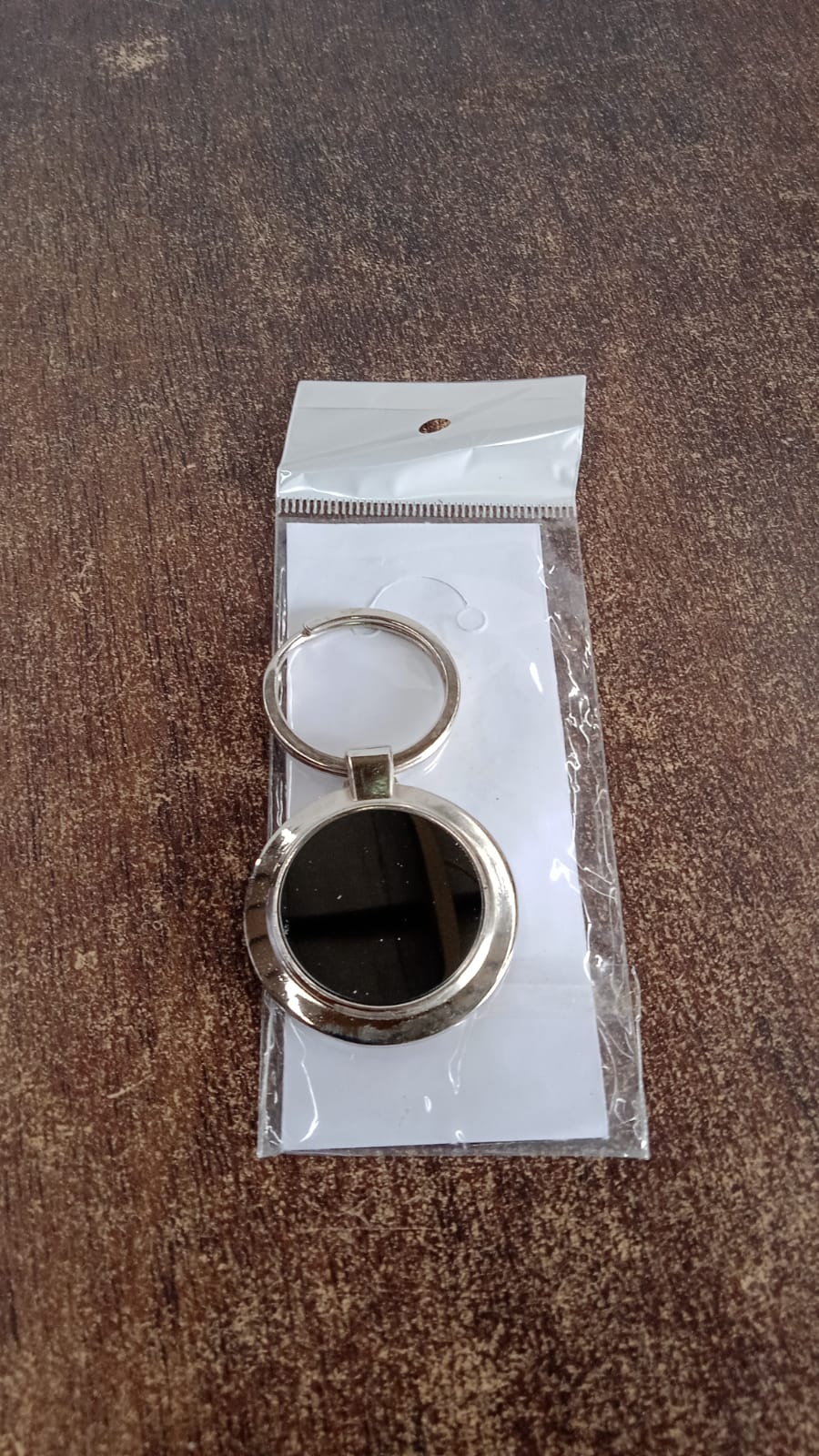 Close-up of round metal keychain with sleek black center and metal rim.