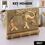 Close-up of the polished gold elephant head and hooks on the wooden key holder.