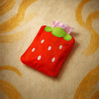 Close-up of a small strawberry hot water bag with a soft fabric cover.