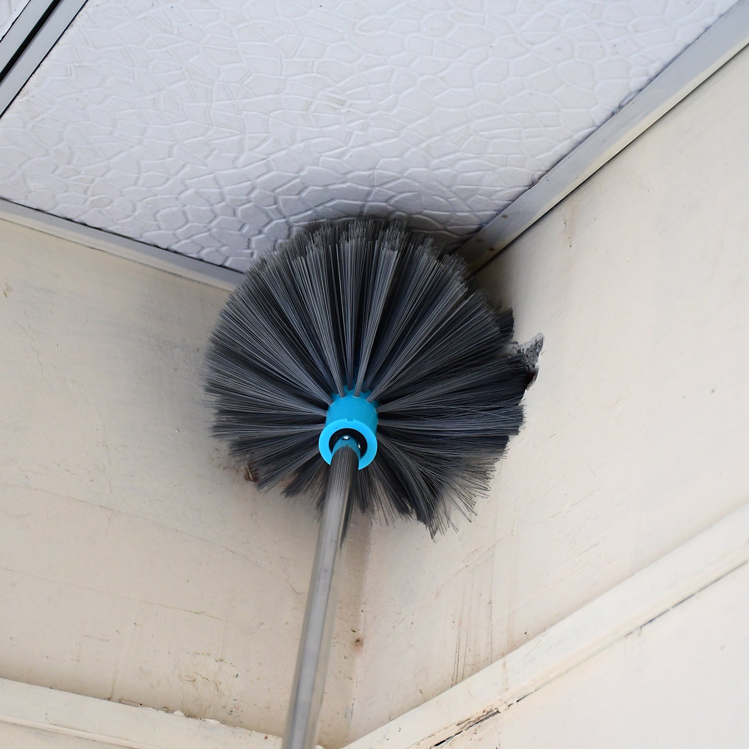 Durable stainless steel handle of the cobweb cleaning brush for sturdy high-reach cleaning.