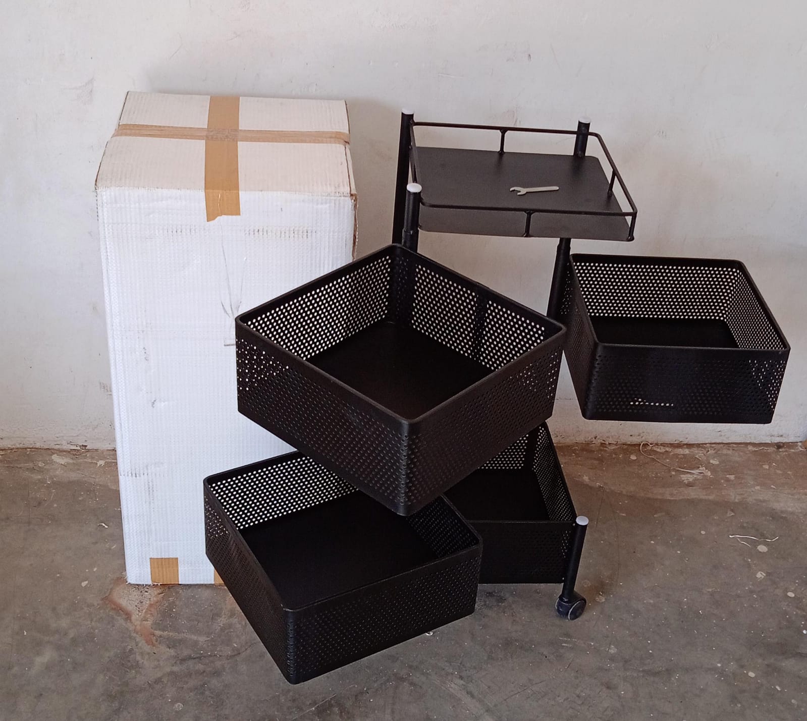 An assembled metal kitchen trolley with wheels, neatly holding various kitchen accessories.