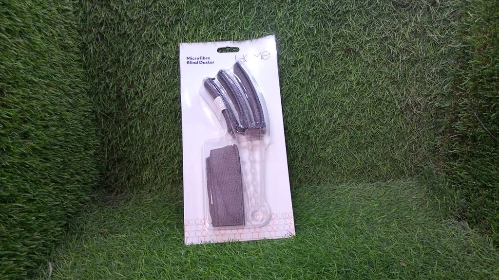 A hand holding the ergonomic handle of the window blind cleaner brush, ready for use.