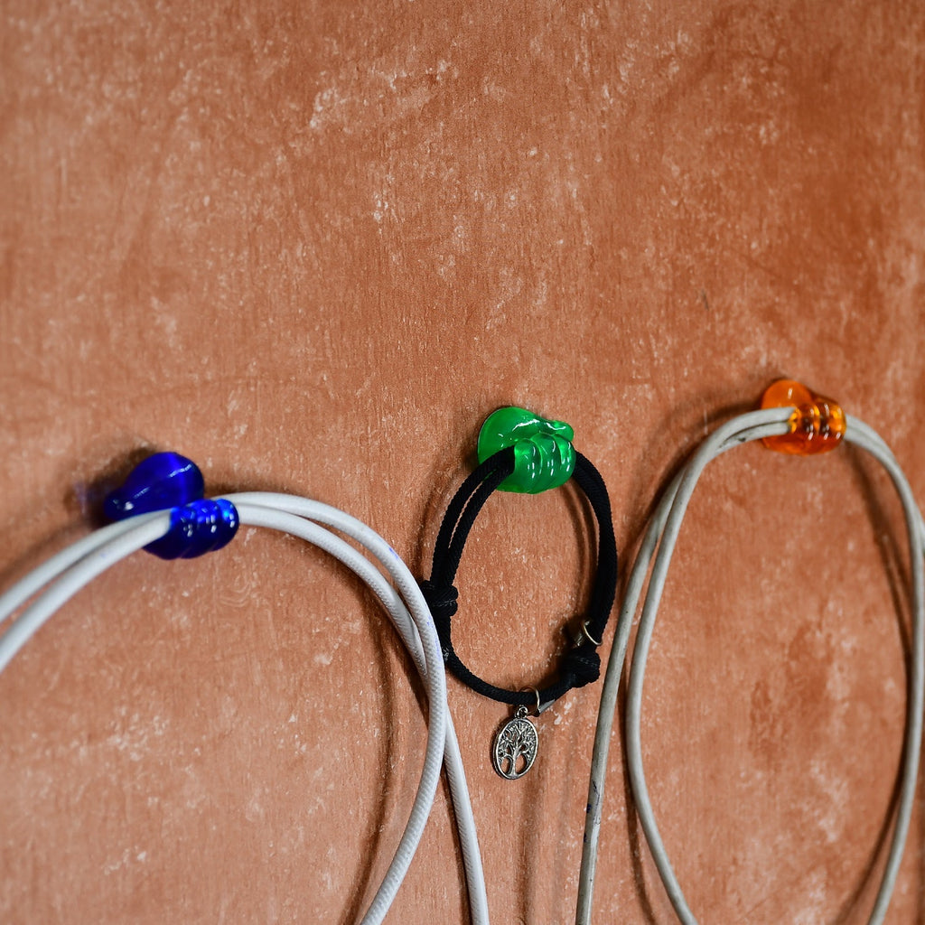 A single hand shape wall clip securing a charging cable against a wall.