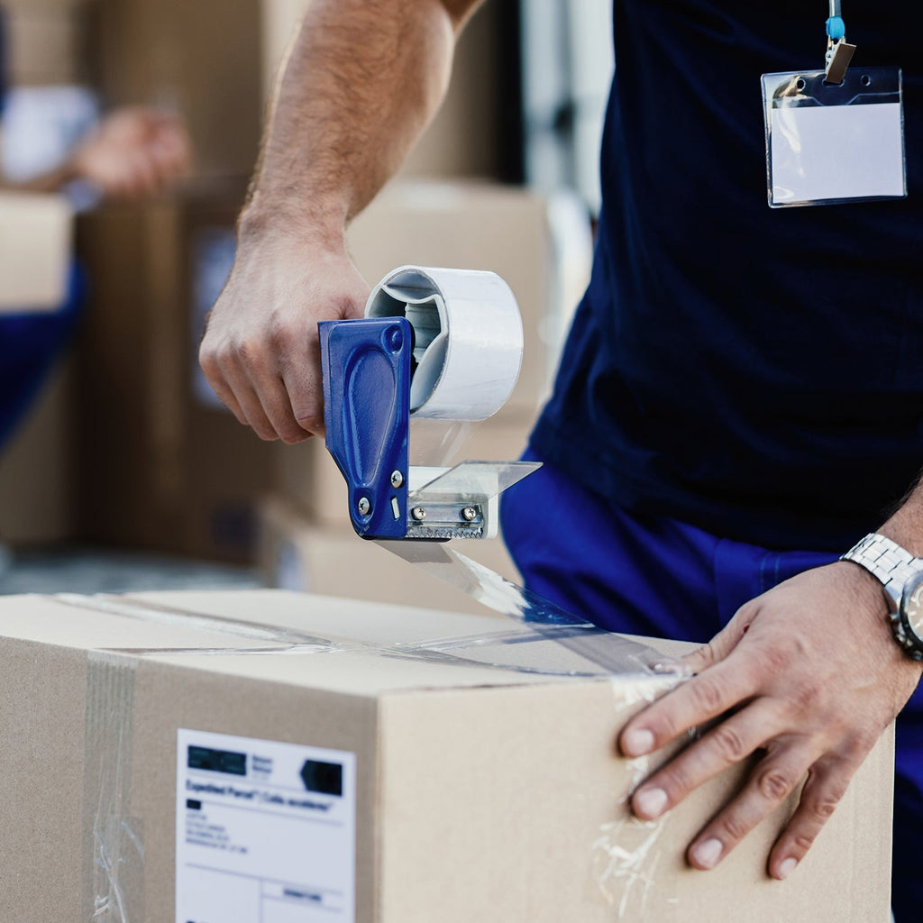 Hand holding a roll of strong adhesive transparent packing tape.