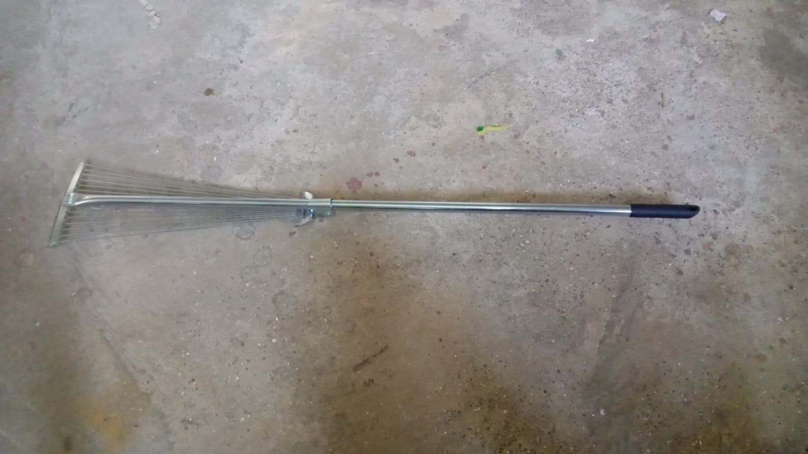 A gardener using the versatile garden rake to smooth soil in a neatly maintained yard.