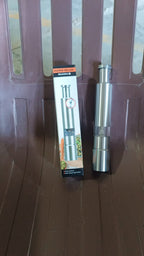 Compact stainless steel thumb press salt and pepper grinder on a wooden surface.