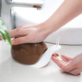 Charming green snail shape soap dispenser on a bathroom shelf.