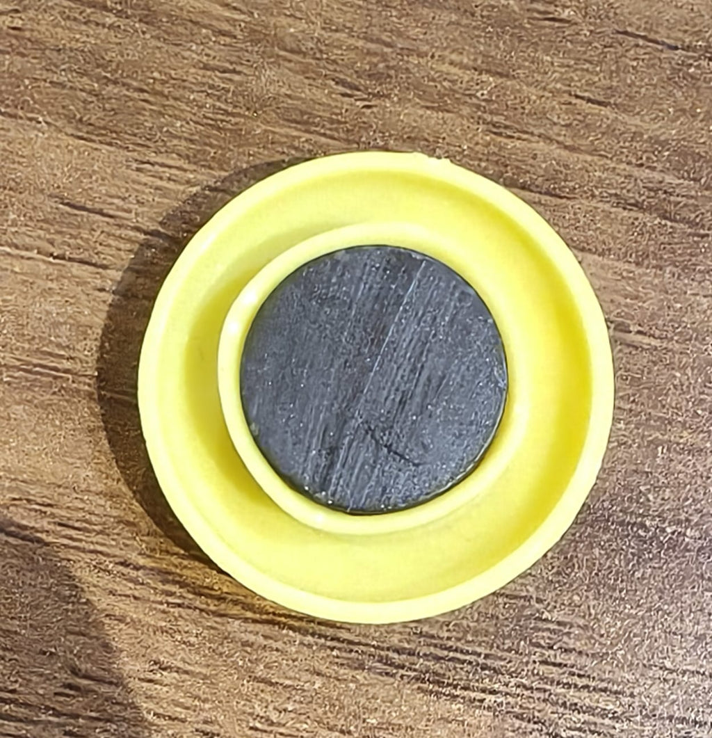 Yellow circular magnet placed next to pen for size reference