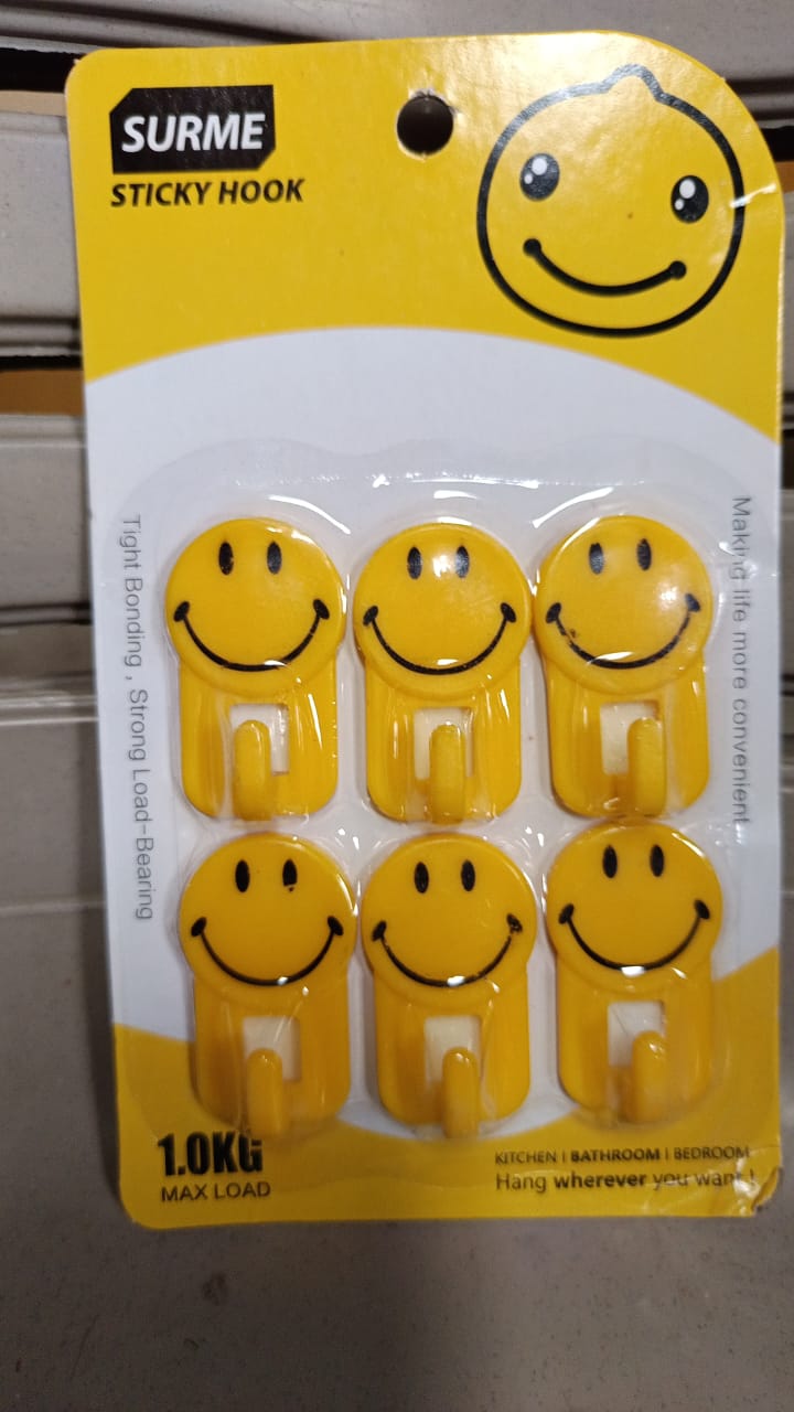 A yellow smiley face adhesive hook against a white background, ready for use.