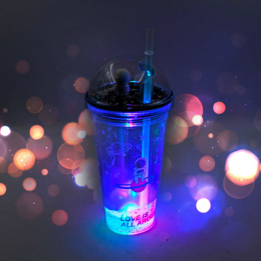 Child holding a glowing astronaut tumbler with a straw, showcasing its double-wall design.