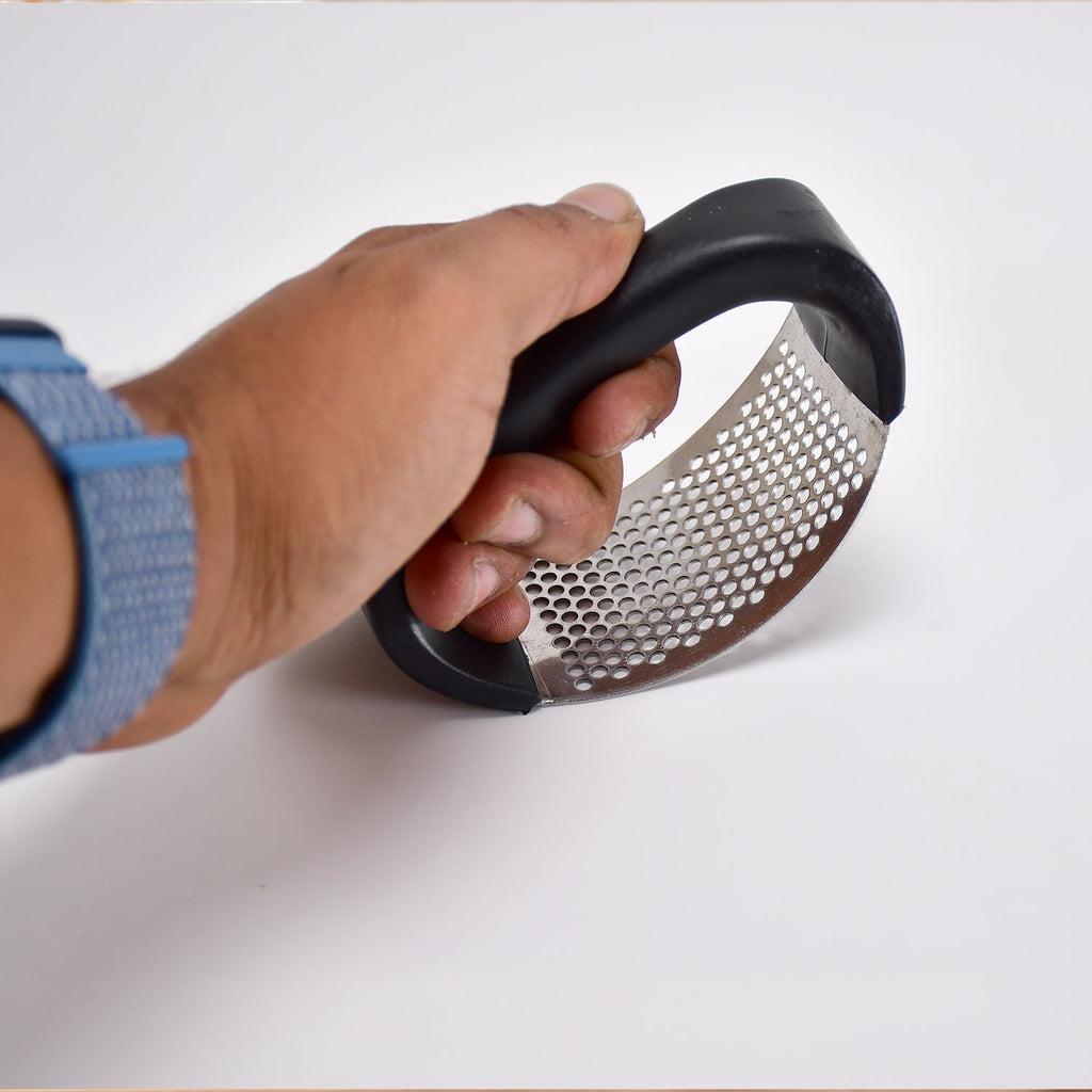 Sturdy stainless steel garlic crusher positioned to highlight its robust construction and ease of use.