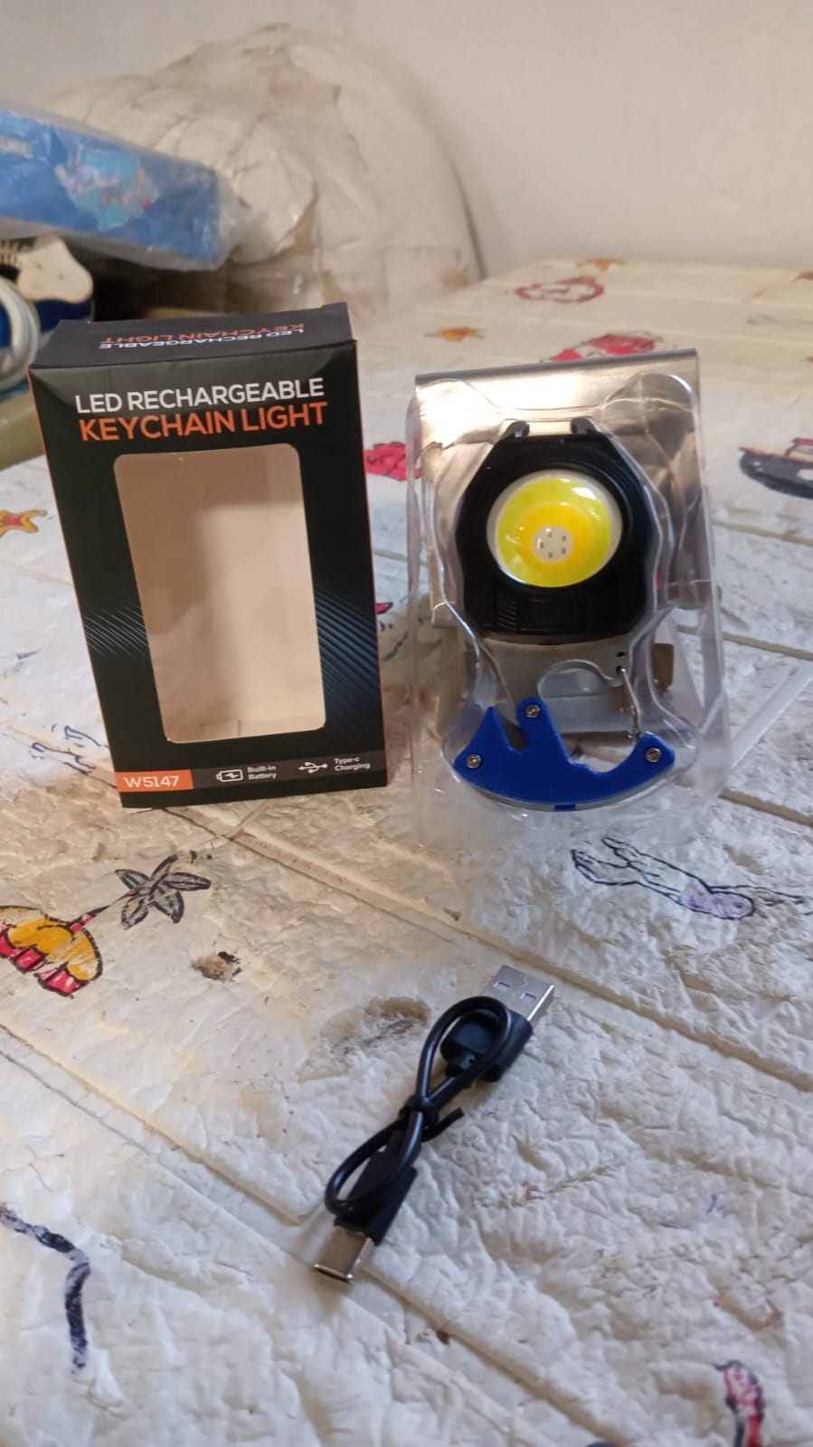 Rechargeable LED keychain flashlight securely attached to a keyring, used outdoors.