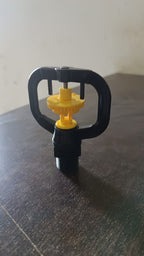 Rotating irrigation sprinkler nozzle actively spraying water in a garden bed.