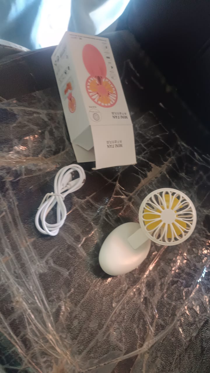 A hand holding the compact Mini USB Handheld Fan, illustrating its portable size.