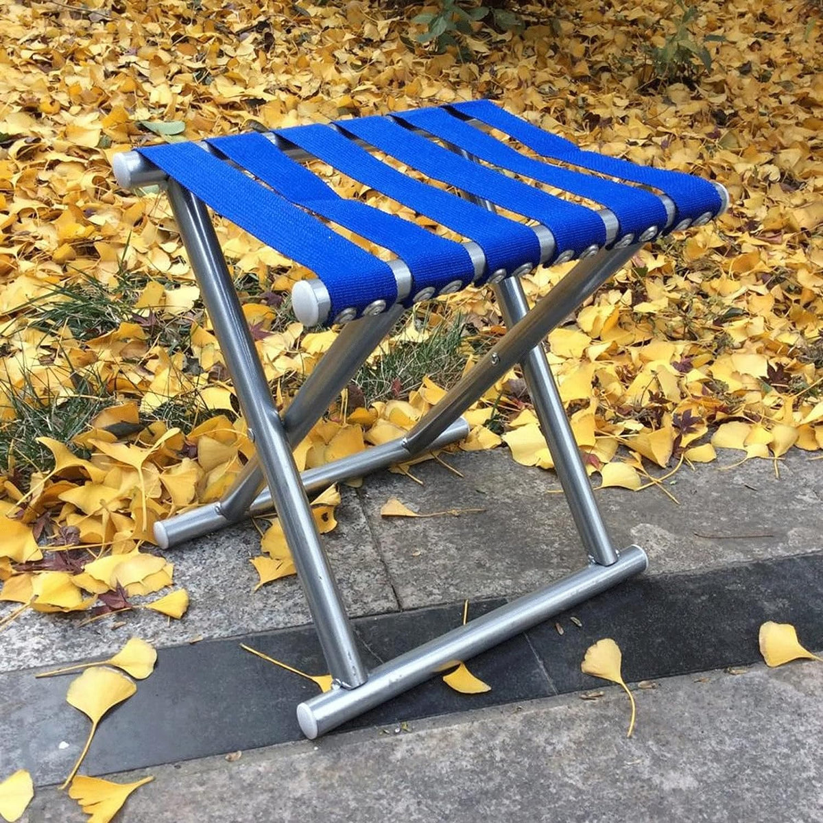 A compact black folding travel stool, ideal for outdoor adventures, displayed against a white background.