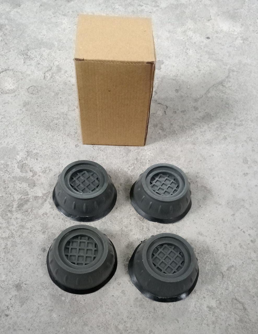 Clear visual of the anti-walk pads installed under a washing machine, providing a stable lifting base.