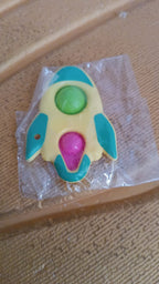 Rocket fidget keychain toy next to measuring tape showing dimensions