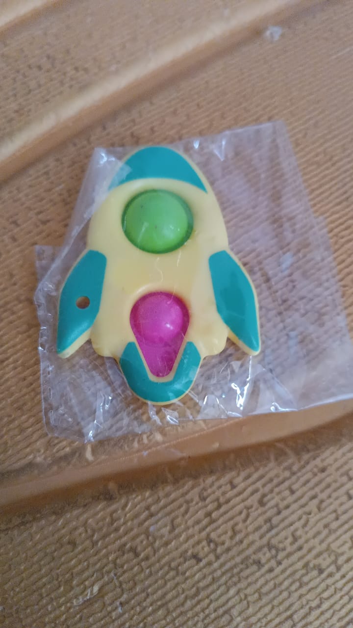 Rocket fidget keychain toy next to measuring tape showing dimensions